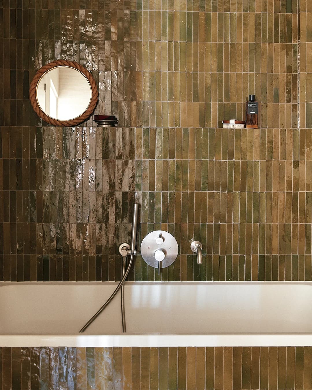 Shower walls in green Zellige baguettes with ochre nuances.
